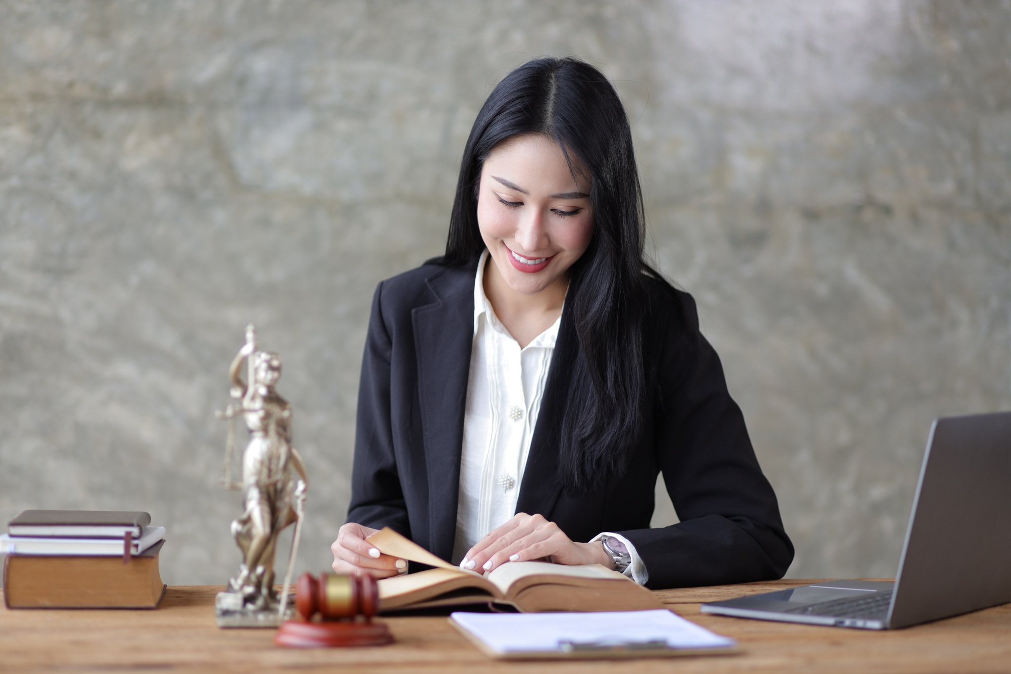 Charming young woman lawyer is reading a law book and working at a desk in a law firm.
